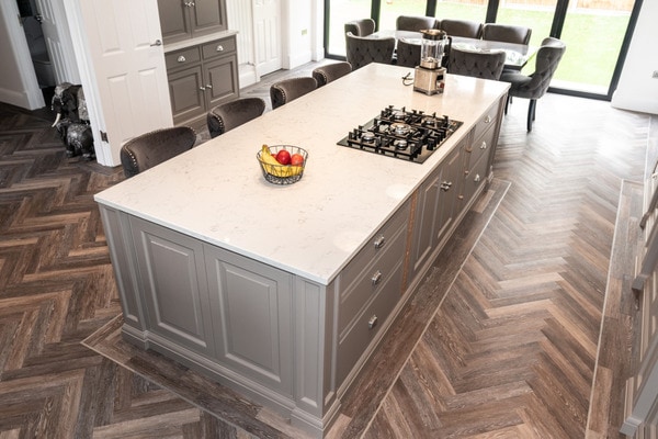 Lát phòng bếp bằng gạch giả gỗ kết hợp với nội thất màu trắng và nâu tạo nên nét đẹp cổ điển cho không gian bếp